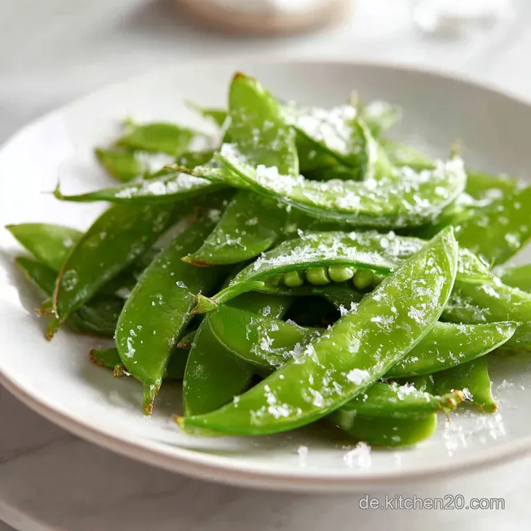 Steaming pile of bright green snow peas tossed with sauteed red pepper, beautifully arranged on a simple white plate.